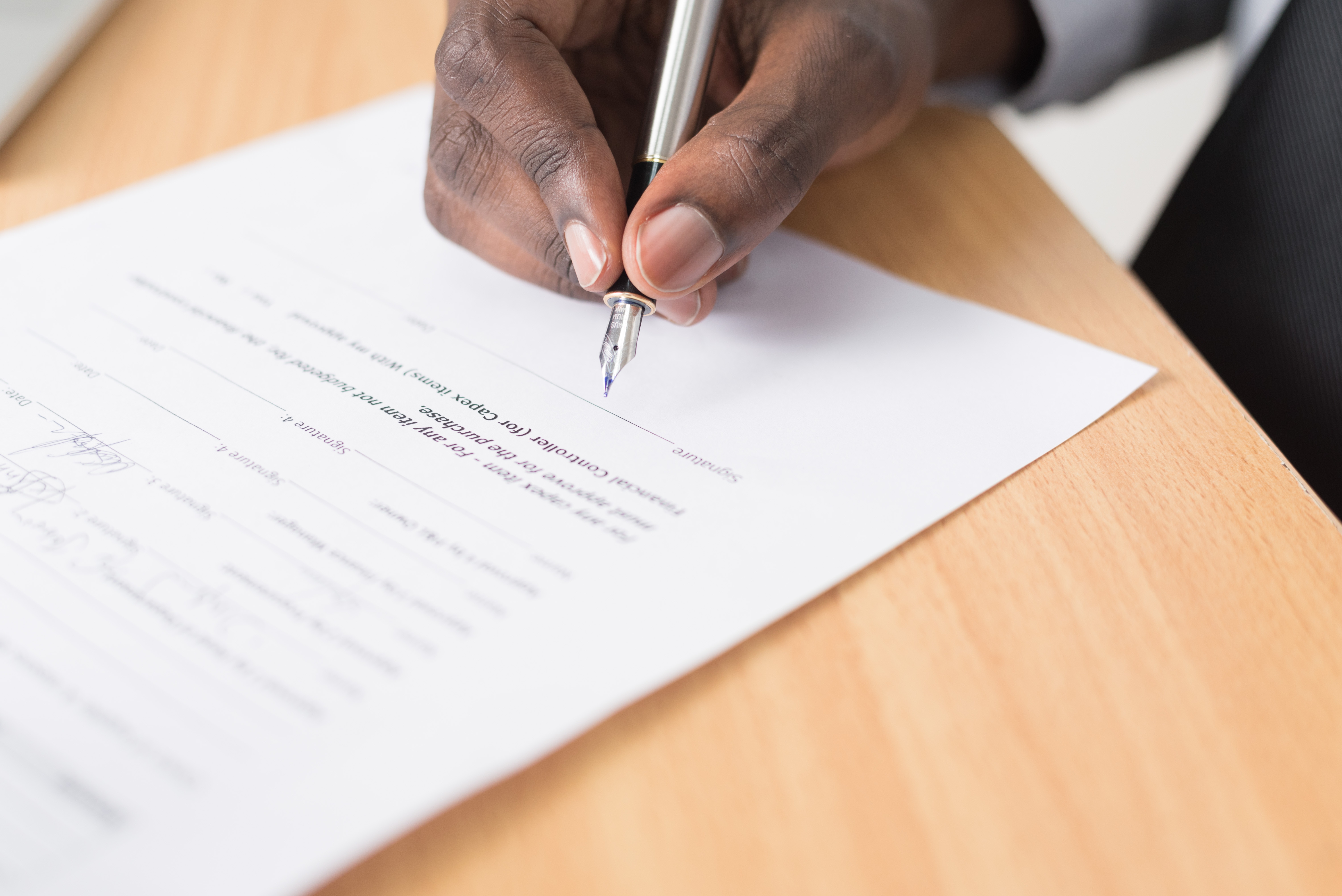 Person signing a paper form with a pen